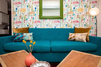 a blue couch in a living room with a mirror at 3BR Loft! Mins to Time Square!, June to Aug 90 days stay required in New York