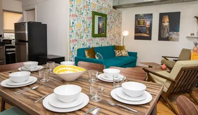 a table with plates and bowls on it in a living room at 3BR Loft! Mins to Time Square!, June to Aug 90 days stay required in New York