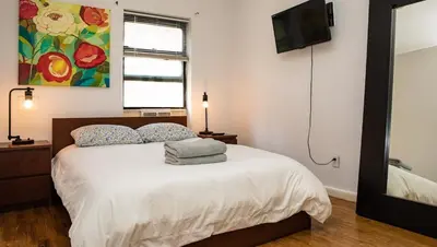 a bedroom with a bed with a television on the wall at 3BR Loft! Mins to Time Square!, June to Aug 90 days stay required in New York