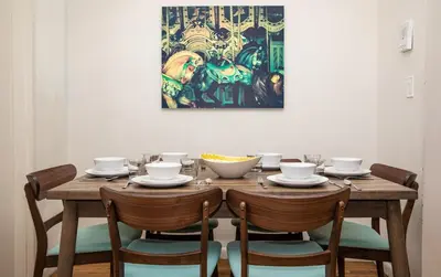 a dining room table with chairs and a painting on the wall at 3BR Loft! Mins to Time Square!, June to Aug 90 days stay required in New York