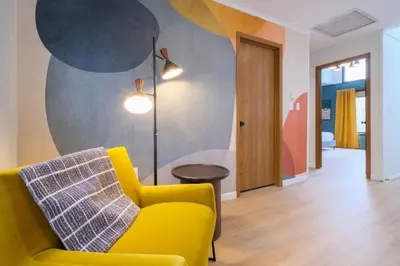 a living room with a yellow couch and a lamp at Scandinavian Retreat Hot Tub, Pool, Game Rm in Gouldsboro