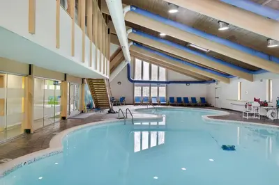 a large pool in a building with blue water at Scandinavian Retreat Hot Tub, Pool, Game Rm in Gouldsboro