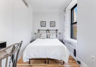 a white bedroom with a bed and a window at Chelsea 2BR Gem! in New York