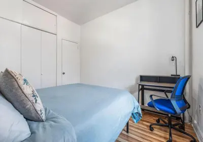 a bedroom with a blue chair and a desk at Chelsea 2BR Gem! in New York