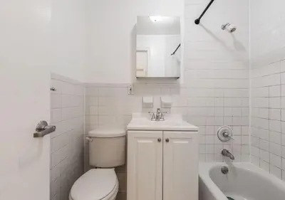 a white bathroom with a toilet and a sink at Chelsea 2BR Gem! in New York