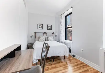 a white bedroom with a bed and a window at Chelsea 2BR Gem! in New York