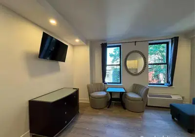 a living room with a table and chairs and a tv at Central Park West Furnished 1 Bedroom Apartment in New York