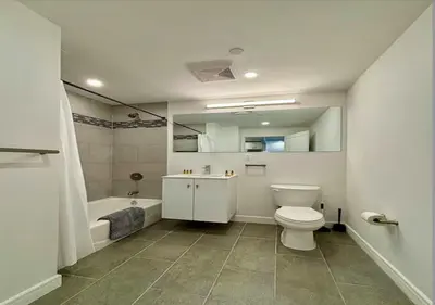 a bathroom with a toilet and a tub and a sink at Central Park West Furnished 1 Bedroom Apartment in New York