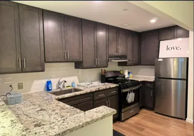 a kitchen with wooden cabinets and a stainless steel refrigerator at Newly Reno 1BR! Murray Hill! in New York