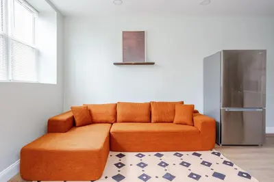an orange couch in a room with a refrigerator at Stylish Stay in Center City, French-Japanese & Minimalist Vibes in Philadelphia