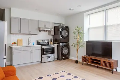 a kitchen with white cabinets and a tv in it at Stylish Stay in Center City, French-Japanese & Minimalist Vibes in Philadelphia