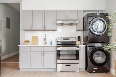 a kitchen with white cabinets and a stove and a washer at Stylish Stay in Center City, French-Japanese & Minimalist Vibes in Philadelphia