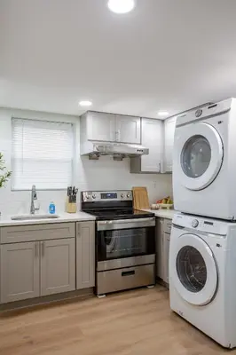 a kitchen with white cabinets and a washer and dryer at Stylish Stay in Center City, French-Japanese & Minimalist Vibes in Philadelphia