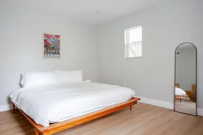 a white bedroom with a bed and a mirror at Stylish Stay in Center City, French-Japanese & Minimalist Vibes in Philadelphia