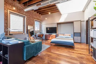 a living room with a bed and a television at Stylish SOHO-Inspired Loft, 15 Min to NYC Times Square in Union City