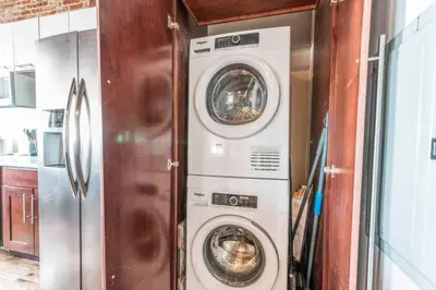 a washer and dryer in a kitchen next to a refrigerator at Stylish SOHO-Inspired Loft, 15 Min to NYC Times Square in Union City