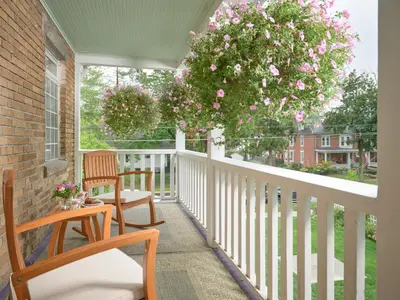 a porch with two chairs and a tree with pink flowers at Mooreland Garden Inn in Carlisle