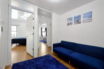 a living room with a blue couch and a bedroom at Cozy 2BR Apartment in the Heart of Chelsea in New York