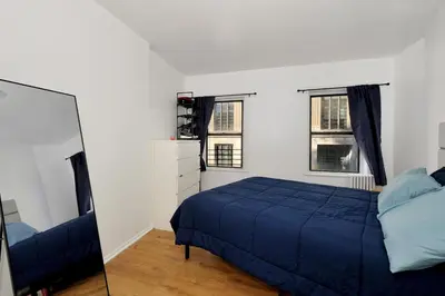 a bedroom with a blue bed and two windows at Cozy 2BR Apartment in the Heart of Chelsea in New York