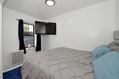 a bedroom with a bed and a flat screen tv at Cozy 2BR Apartment in the Heart of Chelsea in New York