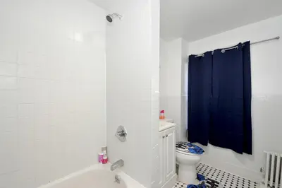 a bathroom with a toilet and a blue shower curtain at Cozy 2BR Apartment in the Heart of Chelsea in New York