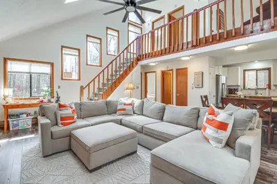 a living room with a couch and a staircase at 3 Mi to Tobyhanna State Park Home with Serene Deck! in Tobyhanna