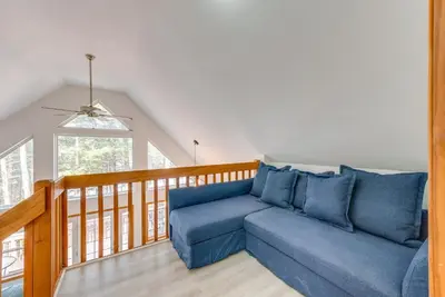 a living room with a blue couch and a balcony at Lakefront Poconos Cabin with Deck and Game Room in Pocono Lake