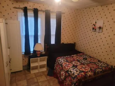 a bedroom with a bed and a window with blue curtains at CareHouse Residence in Lawnside