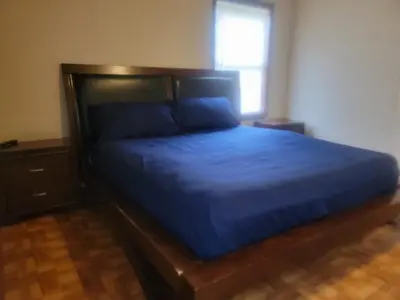 a bedroom with a bed with blue sheets and a window at CareHouse Residence in Lawnside
