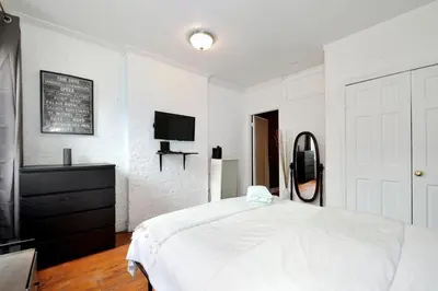 a white bedroom with a bed and a tv at Charming 2BR Apartment Near Times Square in New York