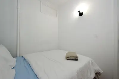 a white bed with a hat on top of it at Charming 2BR Apartment Near Times Square in New York