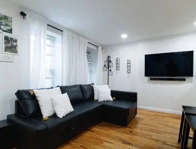 a black couch in a living room with a flat screen tv at Midtown West Furnished 3 Bedroom Apartment in New York
