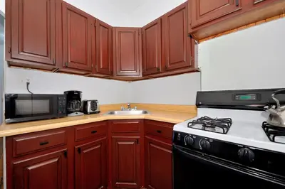 a kitchen with wooden cabinets and a stove top oven at Midtown West Furnished 3 Bedroom Apartment in New York