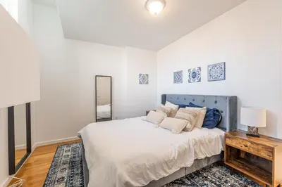 a white bedroom with a bed and a table at Amazing Furnished 1 BR Penthouse Midtown West in New York