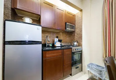 a kitchen with a stainless steel refrigerator and wooden cabinets at 3BR Apartment in Big Apple in New York