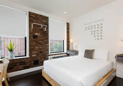 a bedroom with a white bed and a brick wall at Amazing Studio in Kips Bay in New York