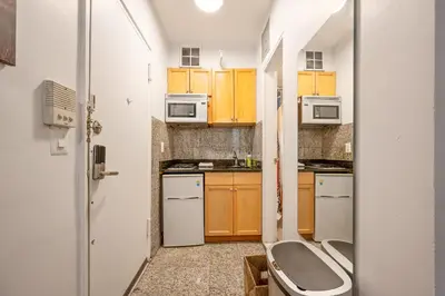 a small kitchen with wooden cabinets and a toilet at Amazing Studio in Kips Bay in New York