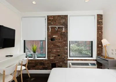 a bedroom with a white bed and two windows at Amazing Studio in Kips Bay in New York
