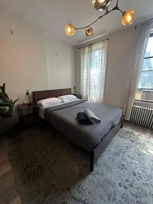 a bedroom with a large bed in a room with windows at Cozy 2BR in NYC Lenox Hill in New York