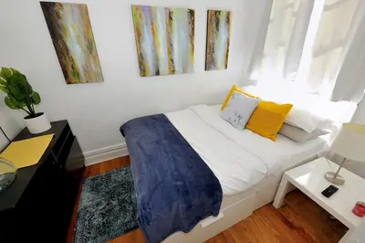 a bedroom with a bed with yellow pillows and a window at Midtown West Furnished Apartment 3BR in New York