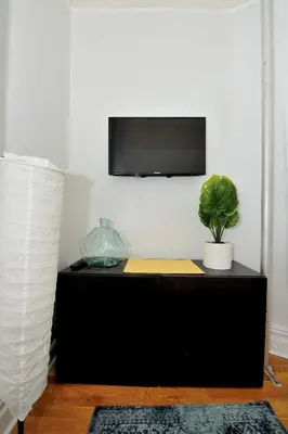 a black cabinet with a tv on a wall with a plant at Midtown West Furnished Apartment 3BR in New York