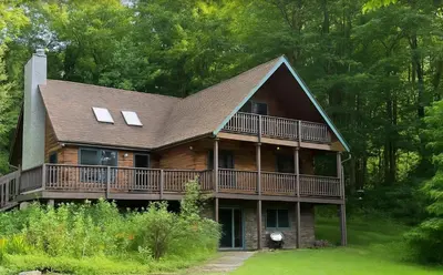 a large wooden house with a large deck at The Log Cabin Near Elk Mountain Ski Slopes in Pleasant Mount
