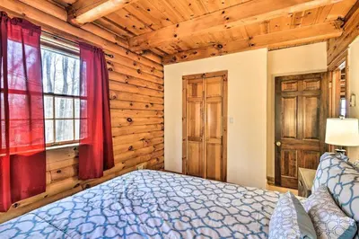 a bedroom with a bed in a room with wooden walls at The Log Cabin Near Elk Mountain Ski Slopes in Pleasant Mount