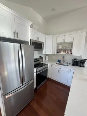 a kitchen with white cabinets and a stainless steel refrigerator at Modern Retreat Poconos 3BR Fire Pit Skiing in East Stroudsburg