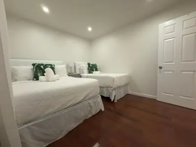 a bedroom with two beds with white walls and wooden floors at Modern Retreat Poconos 3BR Fire Pit Skiing in East Stroudsburg