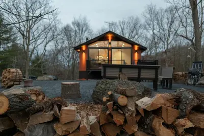 a house with a pile of logs in front of it at Modern Retreat Poconos 3BR Fire Pit Skiing in East Stroudsburg