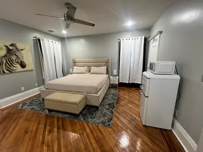 a small bedroom with a bed and a refrigerator at The Grand Parkway is a unique getaway with charm! in East Orange