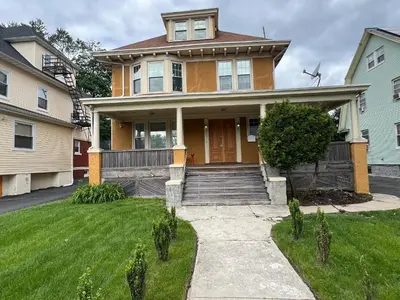 a yellow house with a door and a grass yard at The Grand Parkway is a unique getaway with charm! in East Orange