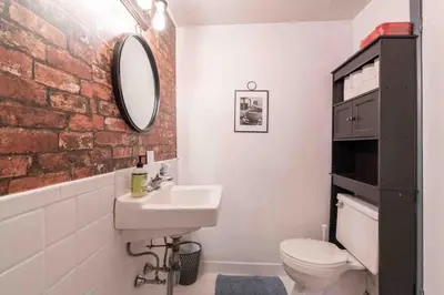 a bathroom with a white sink and a brick wall at 1918 Duplex with Character City Center in Philadelphia