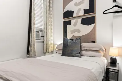 a white bedroom with a bed and a mirror at Micro Studio Walk to Time Square in New York